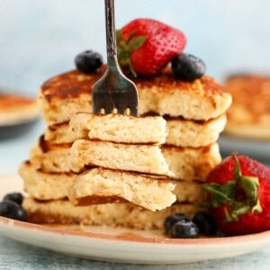 4 eggless pancakes placed on a brown plate along with a fork.