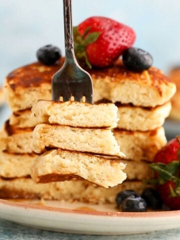 4 eggless pancakes placed on a brown plate along with a fork.