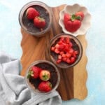 3 glass jars with chocolate strawberry overnight oats on a brown board.