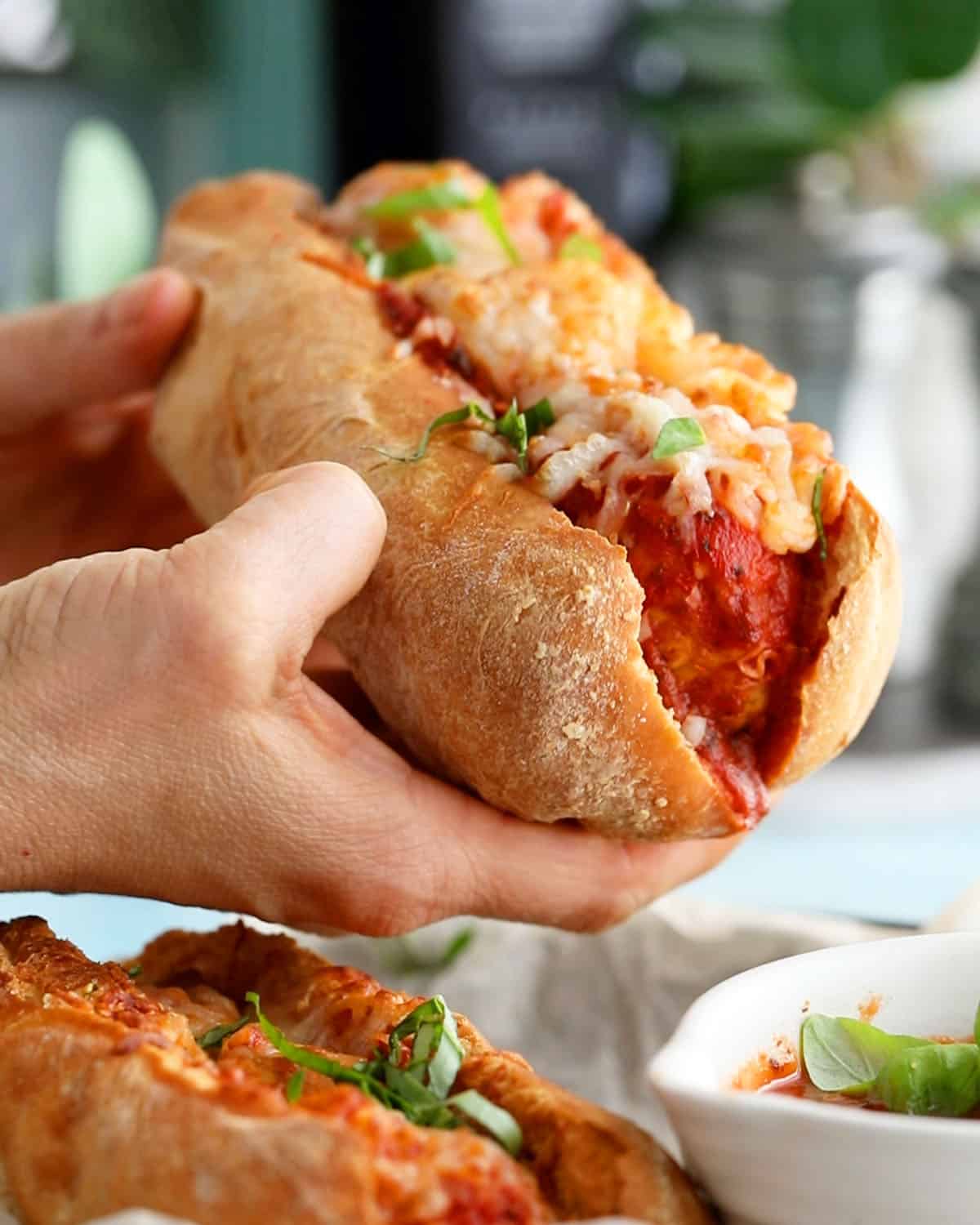 two hands holding on chicken meatball sub.