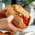two hands holding on chicken meatball sub.