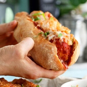 two hands holding on chicken meatball sub.