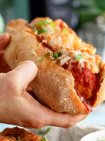 two hands holding on chicken meatball sub.