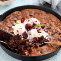 chocolate brownies topped with white ice cream in a black skillet.