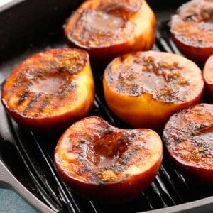 6 grilled peach halves in a black grill pan.