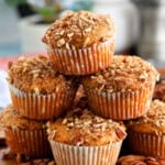 6 orange sweet potato muffins stacked on a brown board.