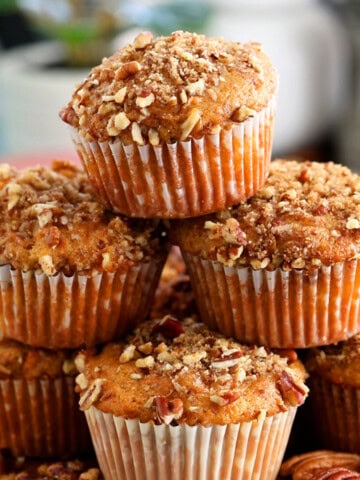 6 orange sweet potato muffins stacked on a brown board.