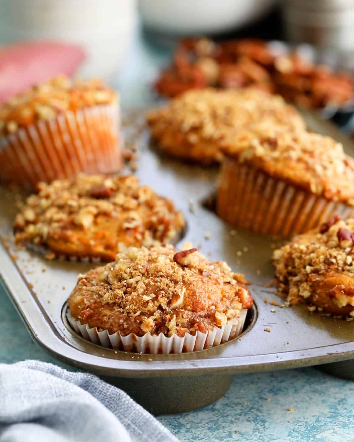 6 orange sweet potato muffins in a metal baking pan.