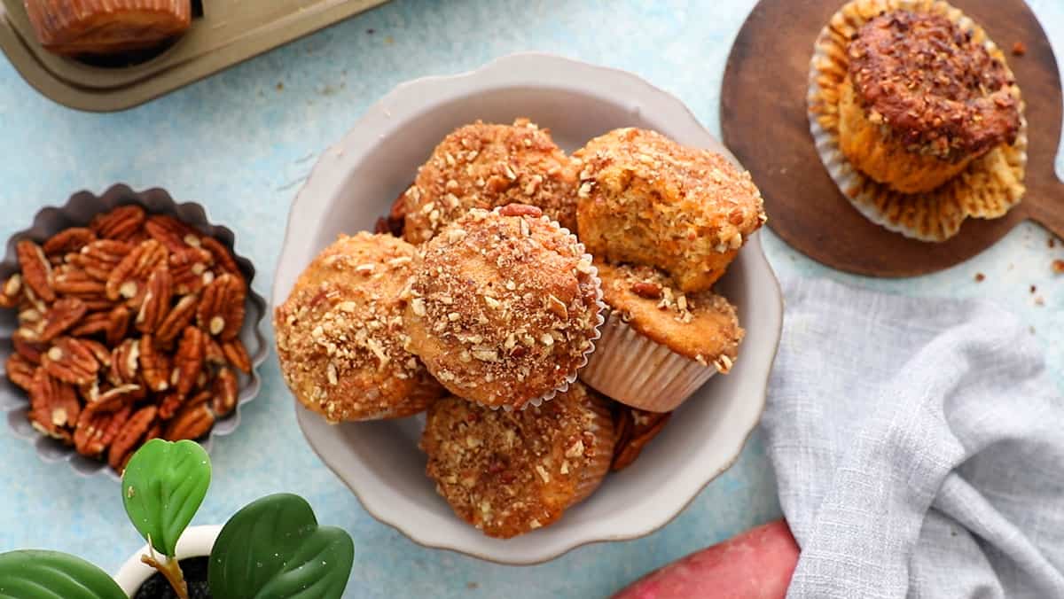 6 orange sweet potato muffins in a white bowl.