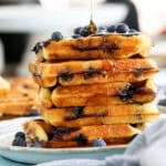 5 blueberry waffles stacked in a white plate.