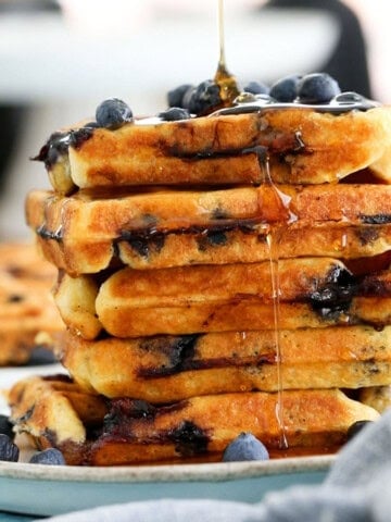 5 blueberry waffles stacked in a white plate.