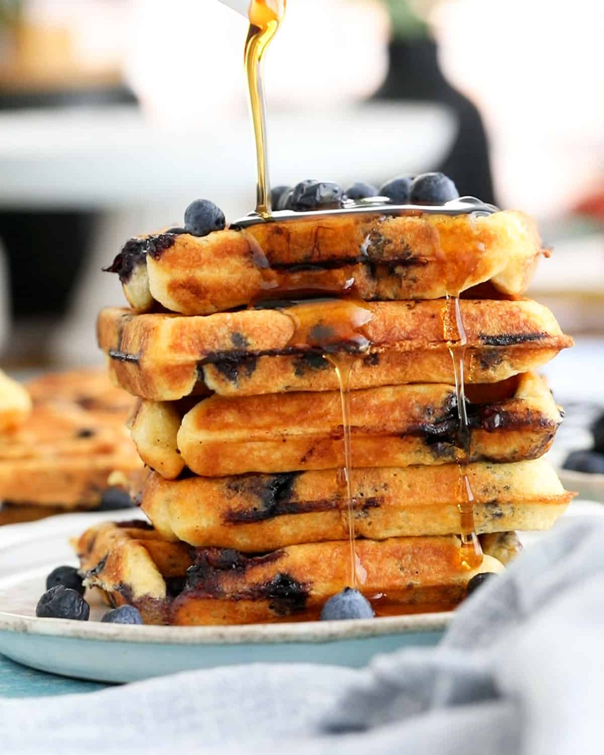 5 blueberry waffles stacked in a white plate.