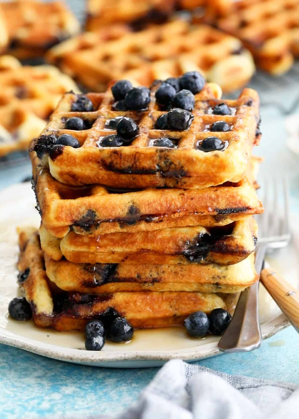5 blueberry waffles stacked in a white plate.