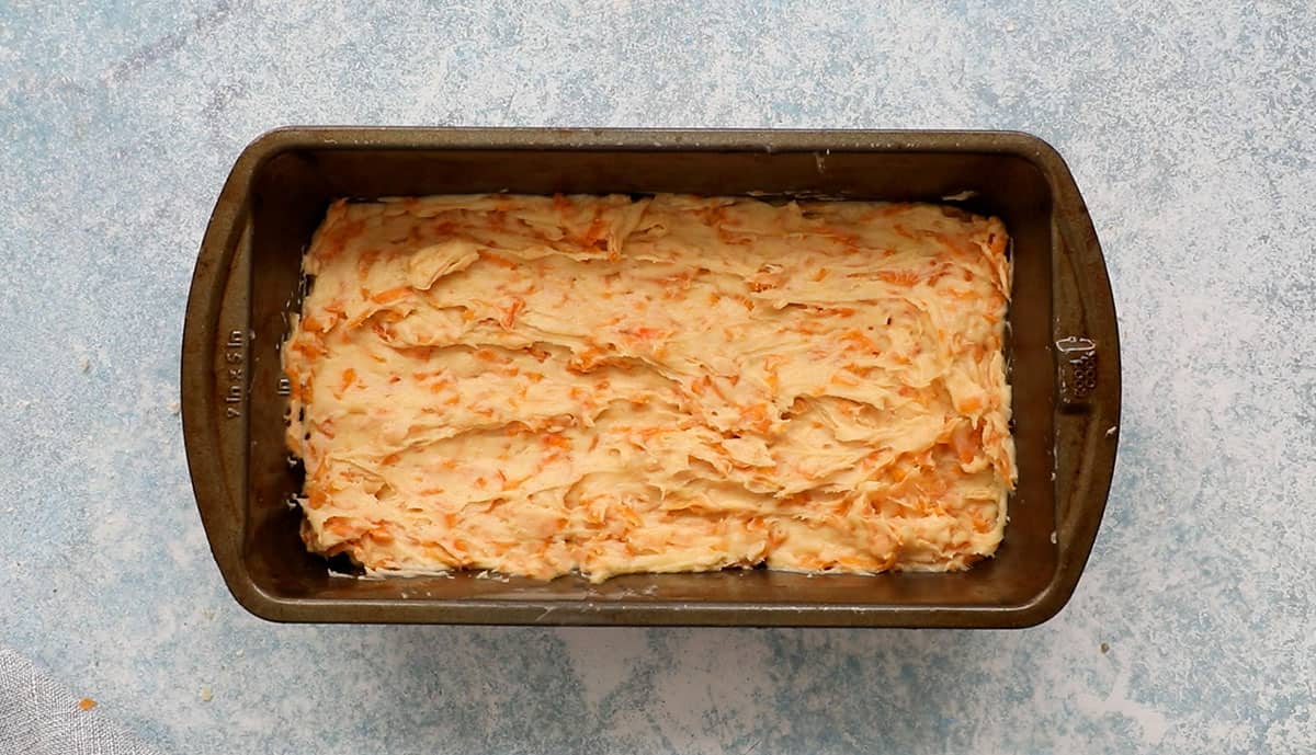 one metal loaf pan filled with persimmon bread batter.