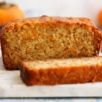 Cut persimmon bread placed on a white marble.