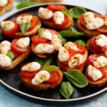 caprese toasts on black plate for Halloween appetizer.