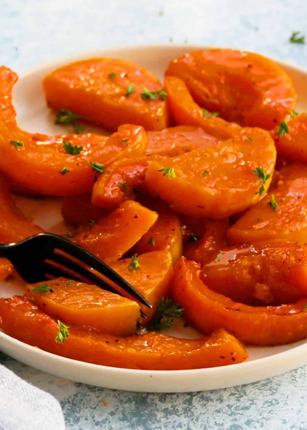orange colored roasted butternut squash wedges in a white plate.