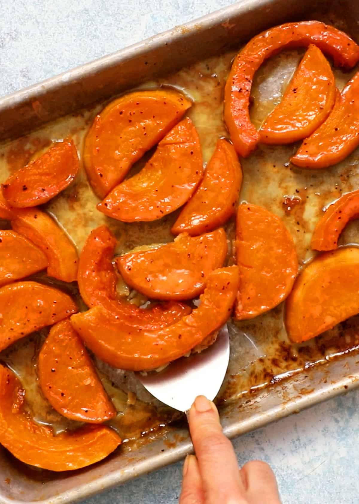 roasted butternut squash wedges in a metal baking sheet.
