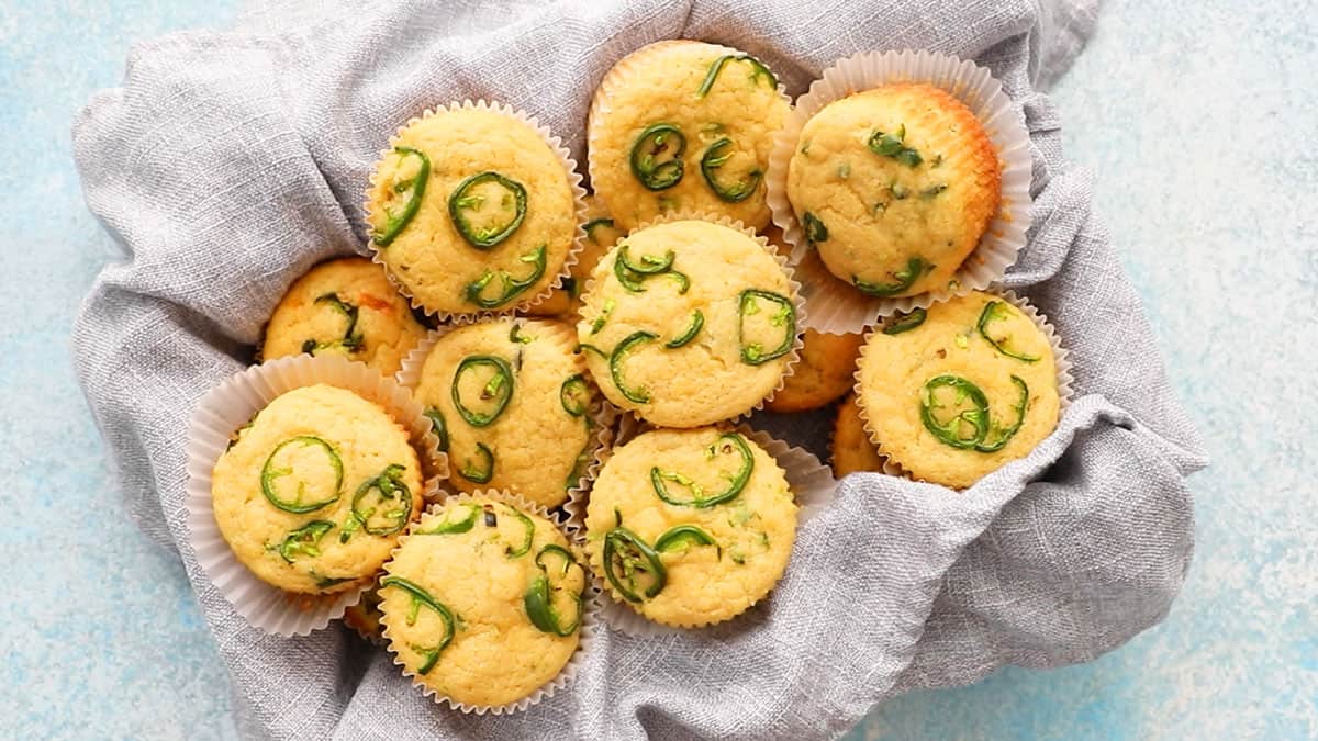 baked yellow corn muffins in a grey kitchen towel.