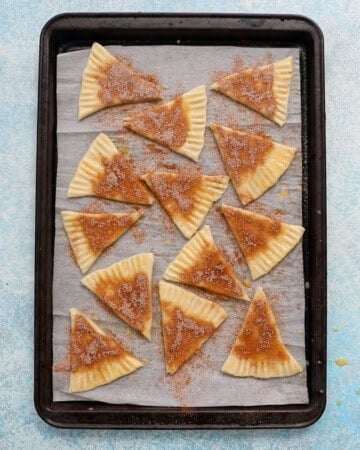unbaked pie crust cookie triangles in a baking sheet.