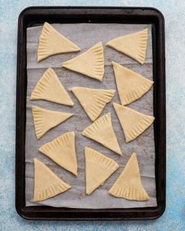 unbaked pie crust cookie triangles in a baking sheet.