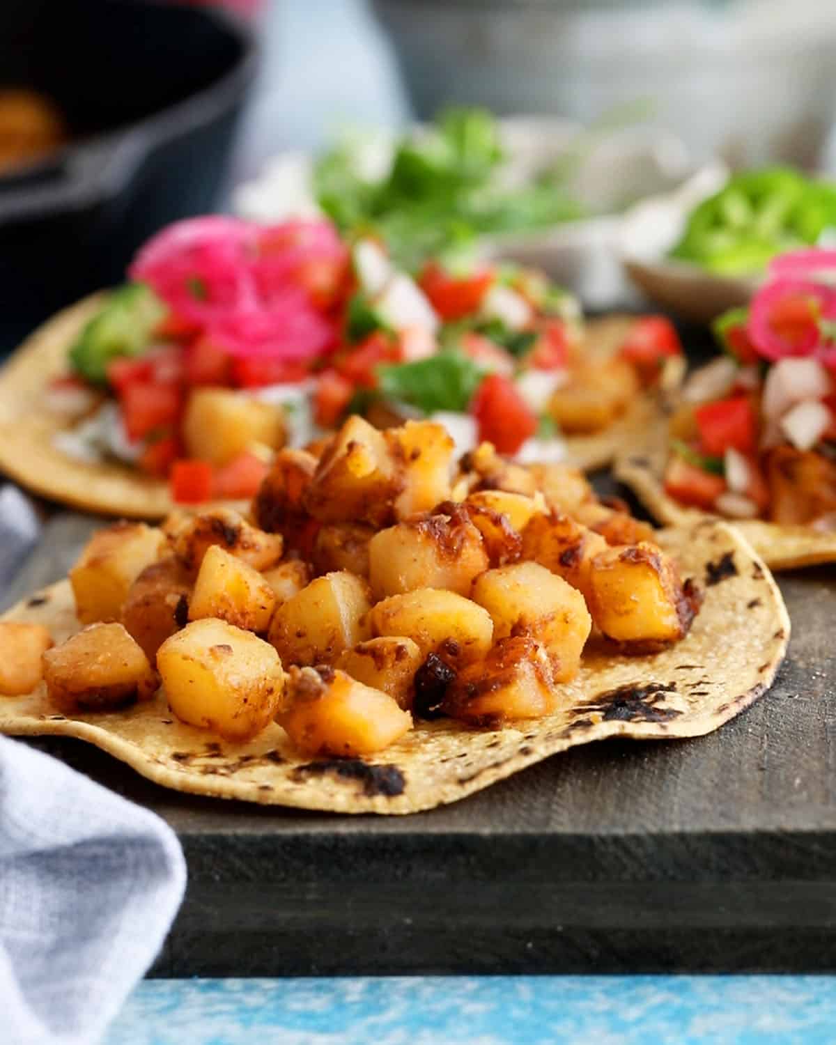 3 yellow potato tacos on a balck board.