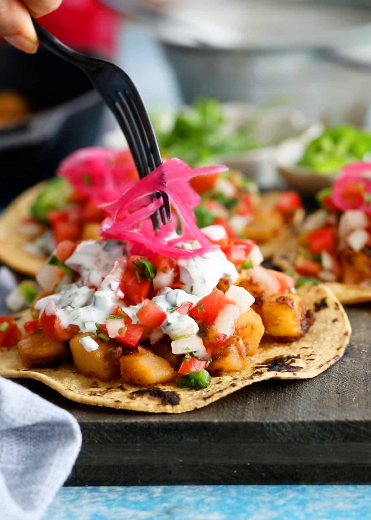 3 yellow potato tacos on a balck board.