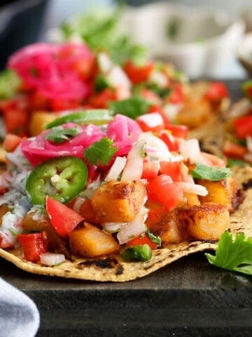 3 yellow potato tacos on a balck board.