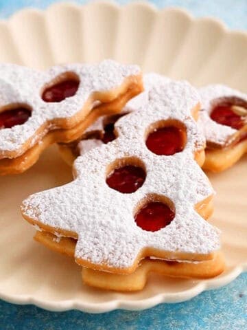 3 Christmas tree shaped cookies placed on a white scalloped plate.