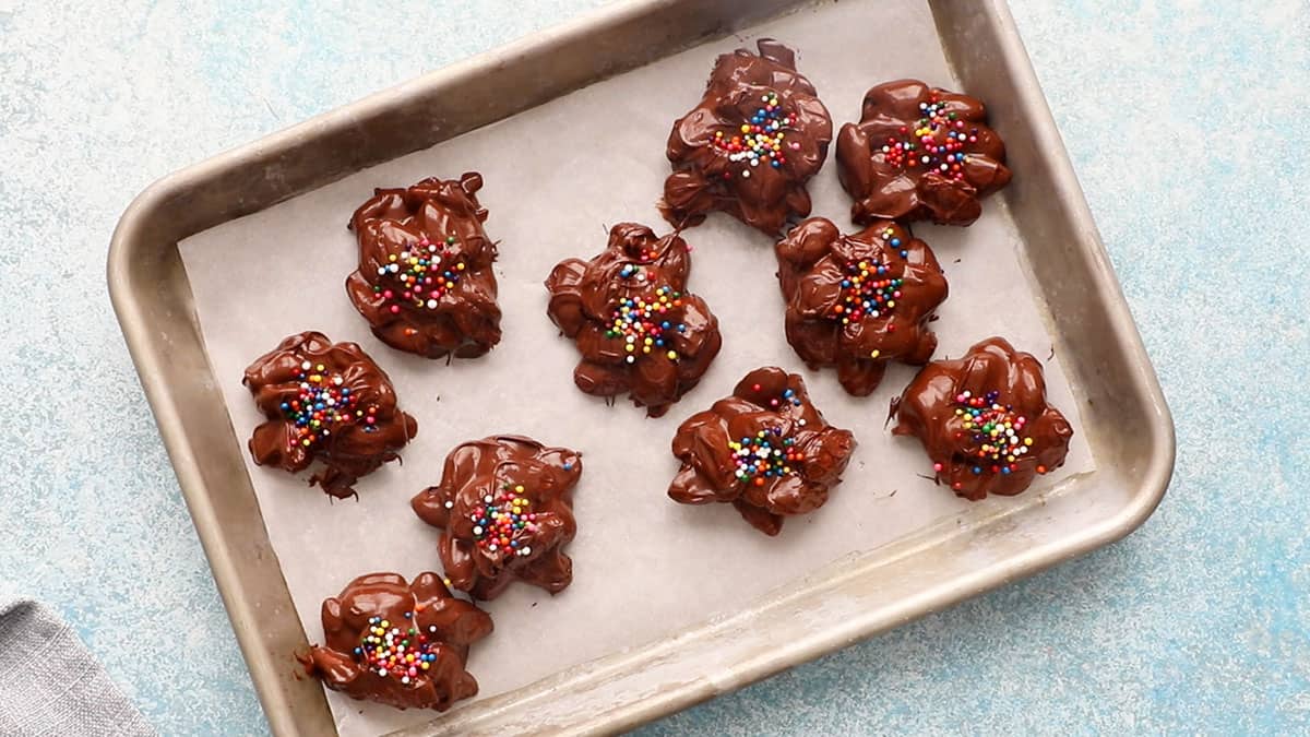 mounds of chocolate almonds in a parchment lined baking sheet.