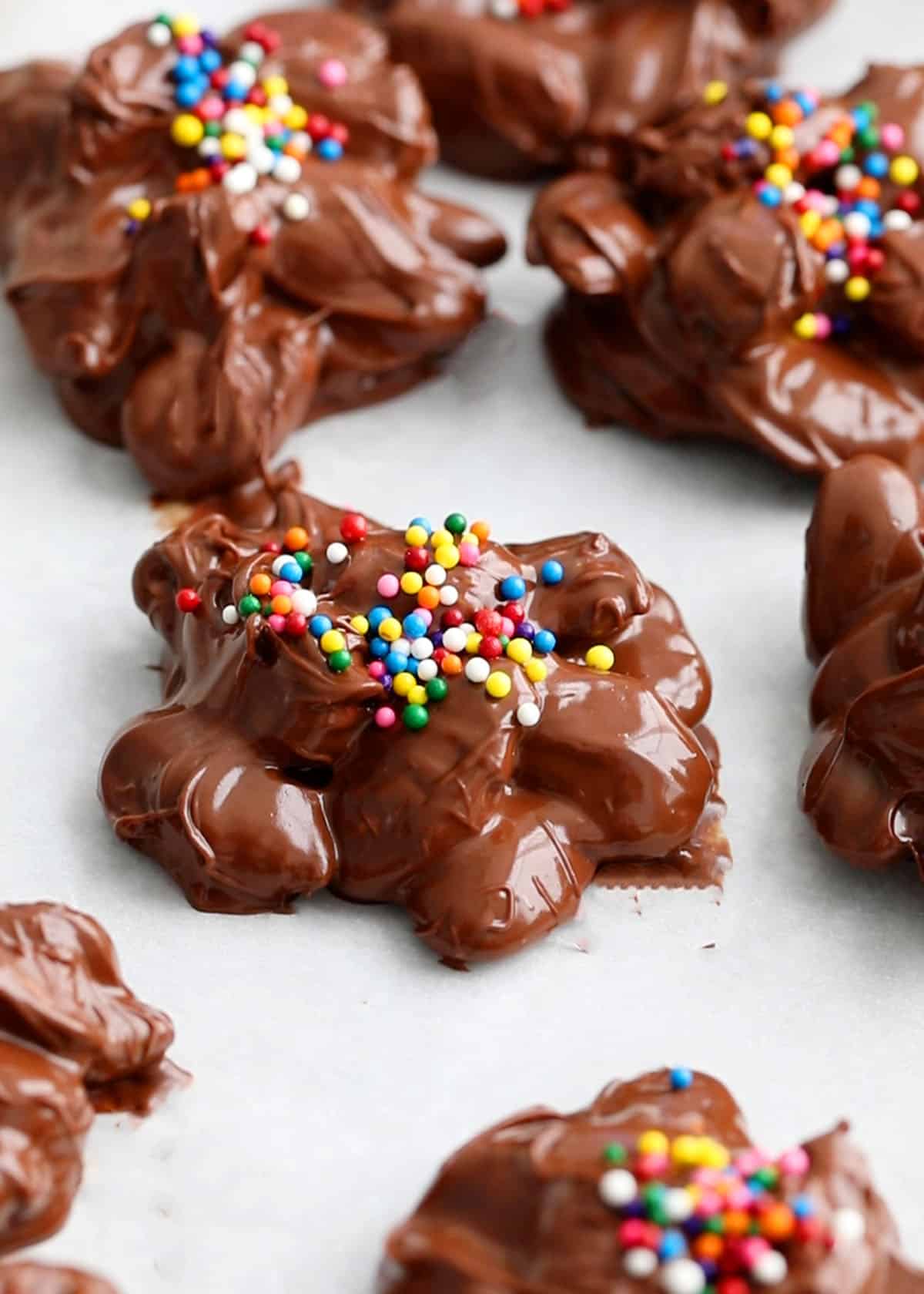 mounds of chocolate almonds in a parchment lined baking sheet.