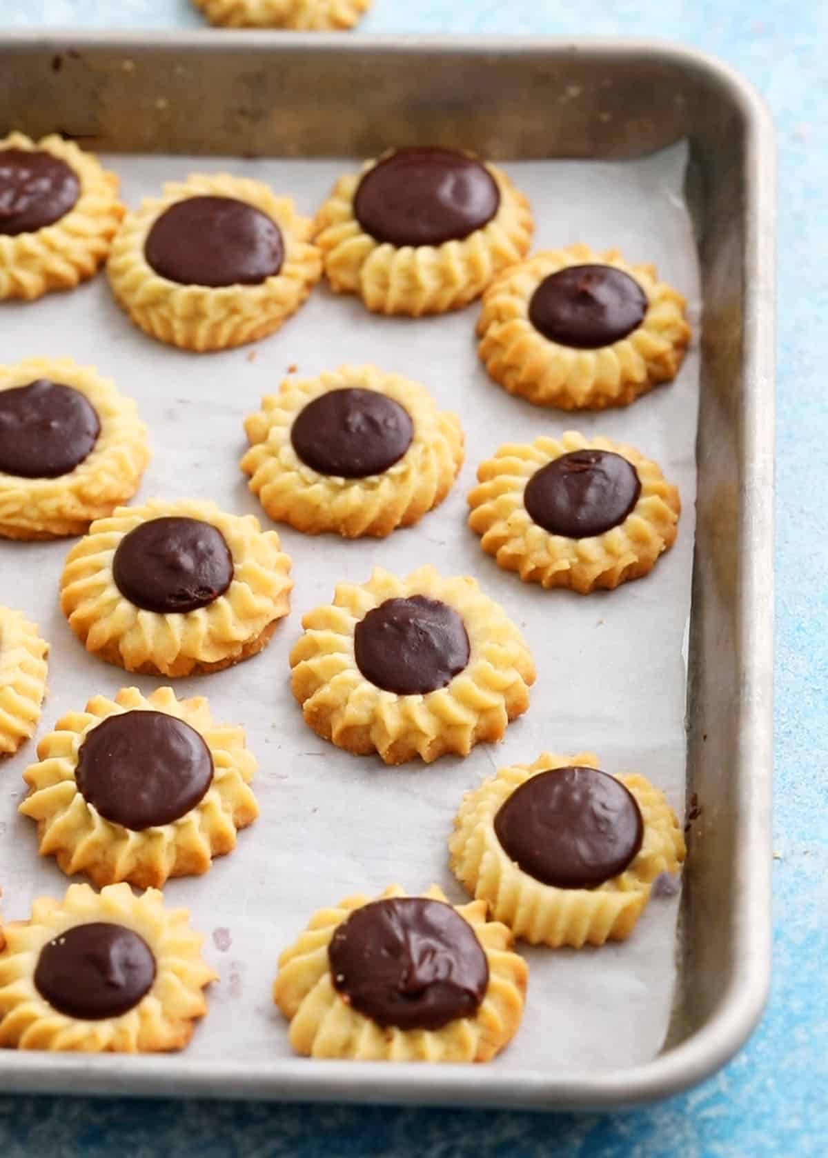 flower shaped butter cookies in a parchment lined baking sheet.