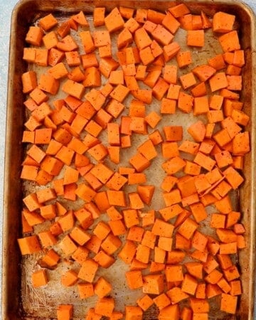 cubed orange sweet potato in a metal baking sheet.