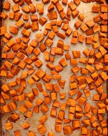 cubed orange sweet potato in a metal baking sheet.