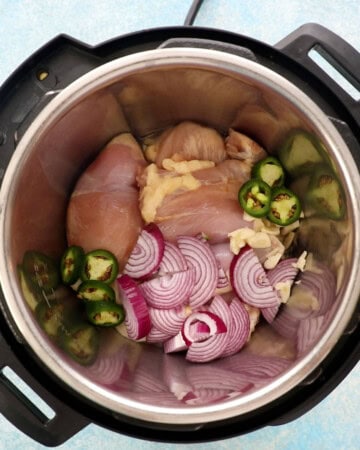 pink chicken, onions, green jalapeno in an instant pot.