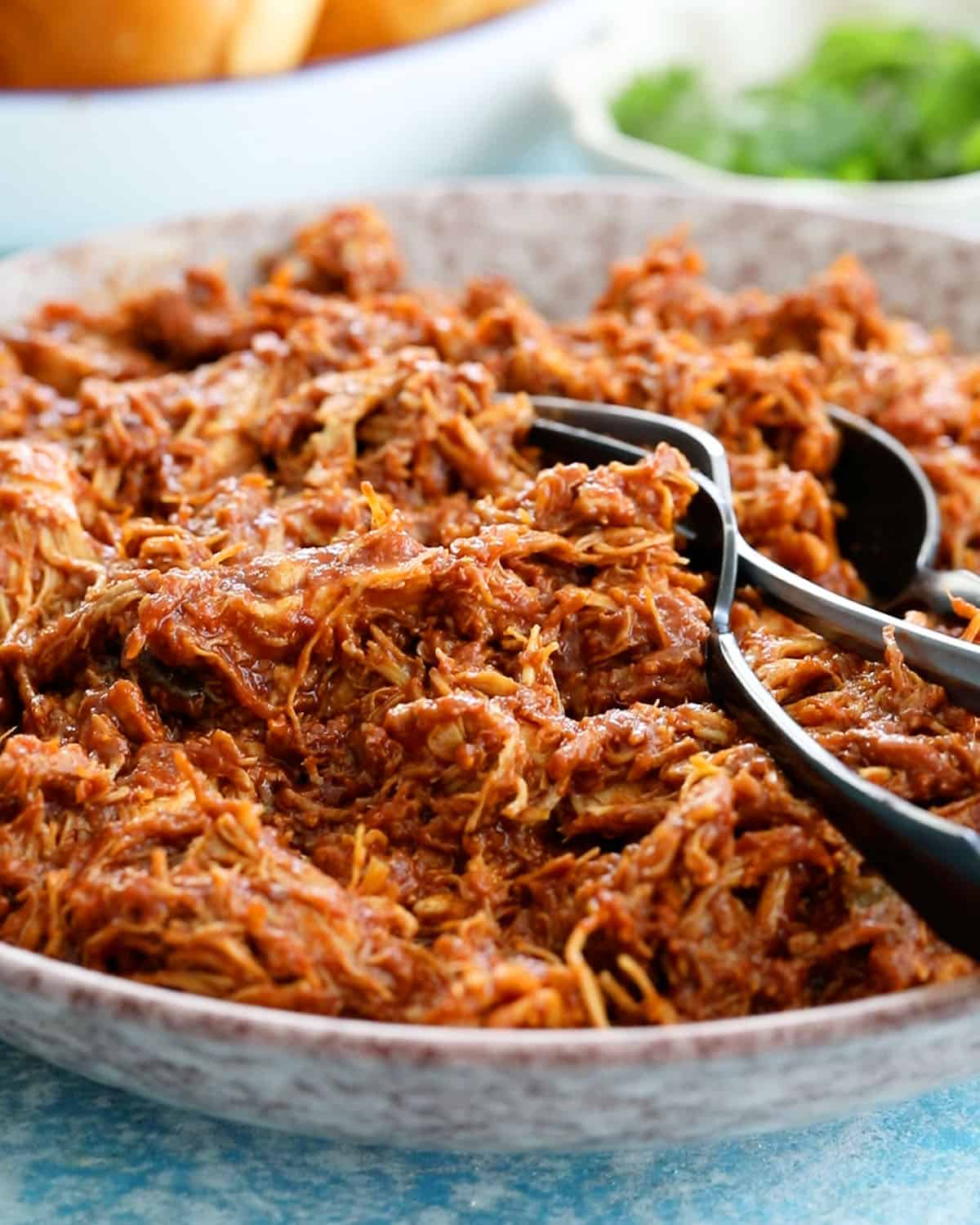 brown shredded bbq chicken in a pink bowl.