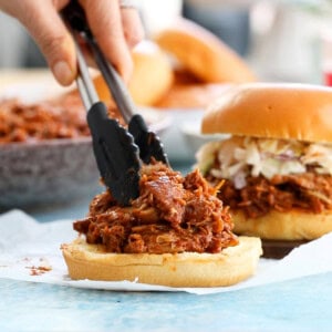 brown bbq chicken over white burger buns.