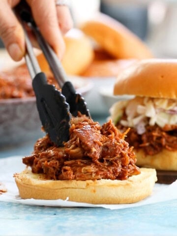 brown bbq chicken over white burger buns.