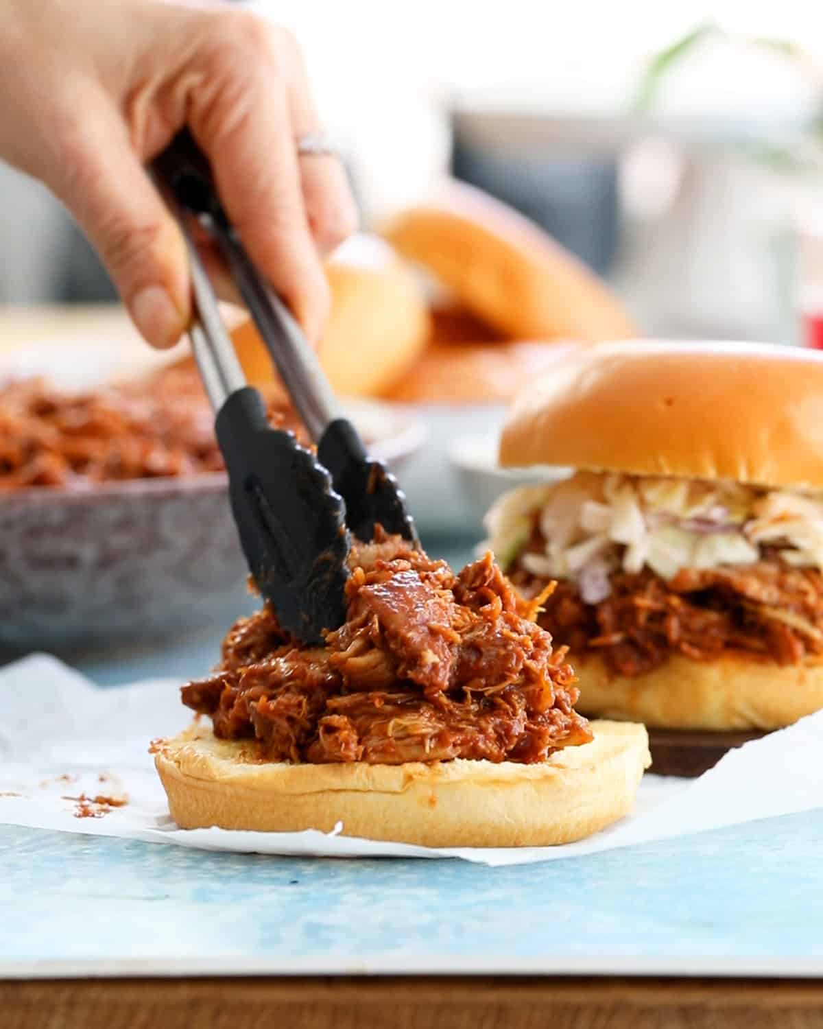 brown bbq chicken over white burger buns.