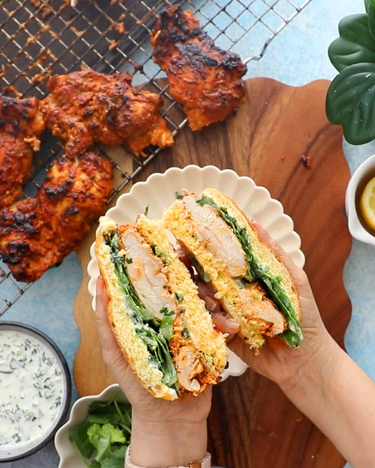 a hand holding a cut tandoori chicken sandwich.