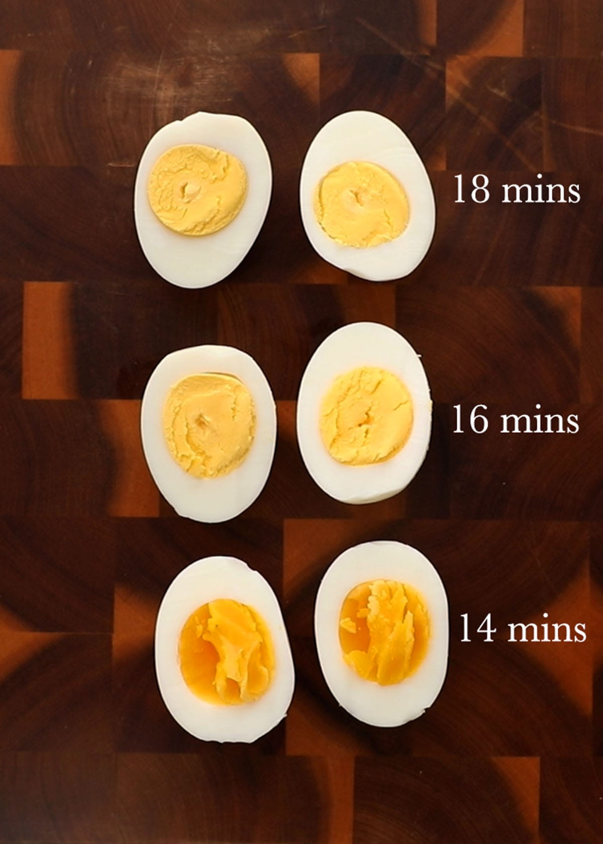 6 boiled egg halves placed in a wooden cutting board.