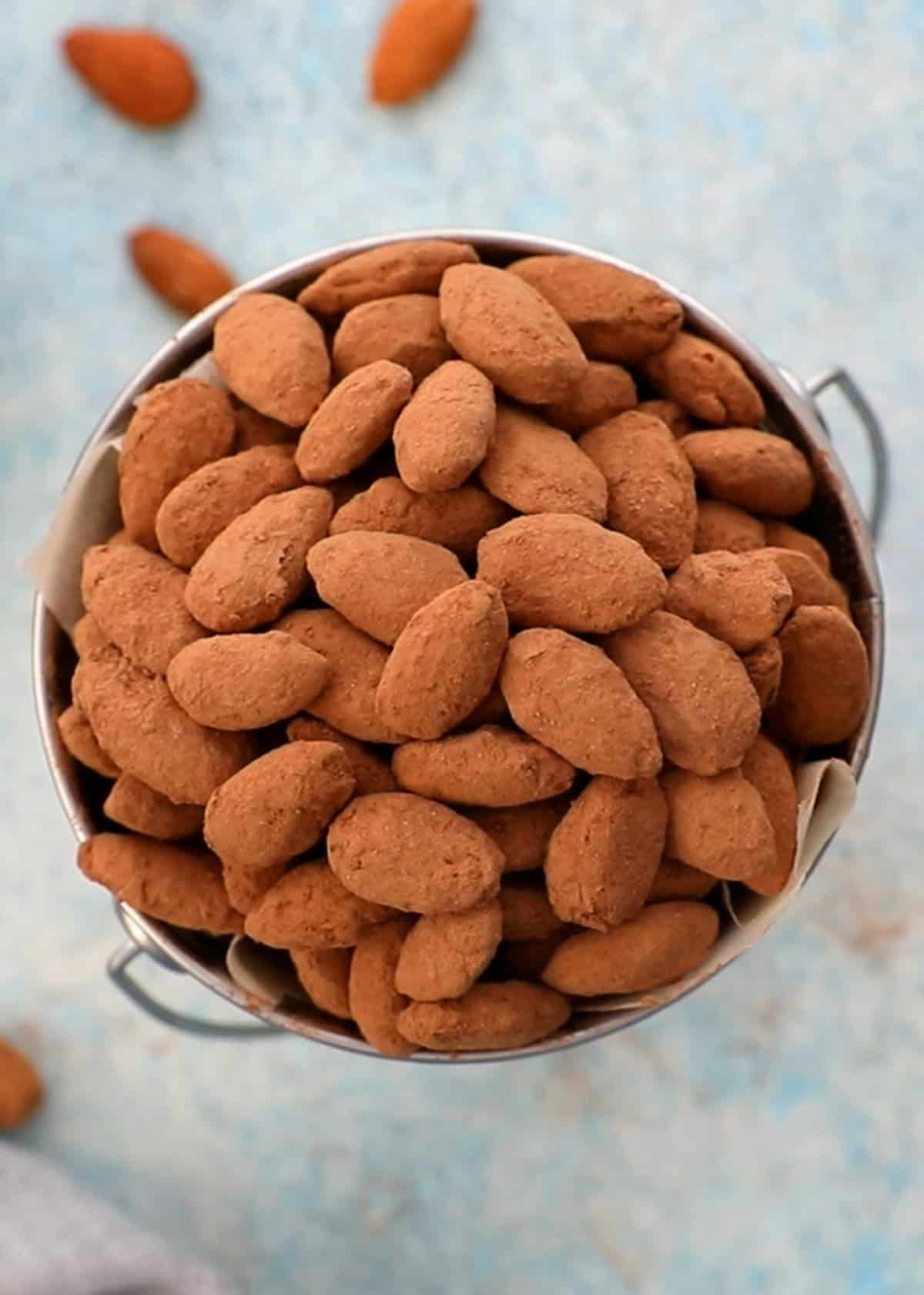 brown cocoa almonds in a metal cup.