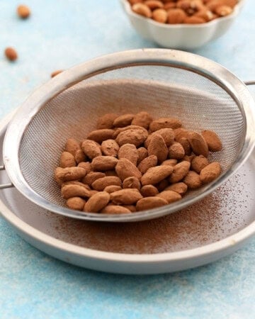 brown cocoa almonds in a metal strainer.