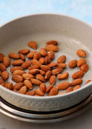 brown almonds in a white skillet.