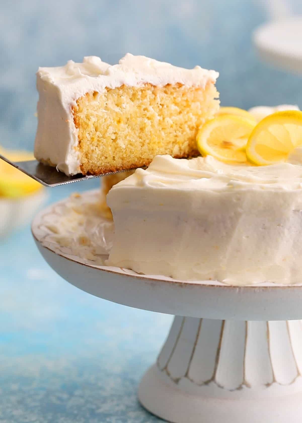 a decorated lemon cake in a white cake stand.