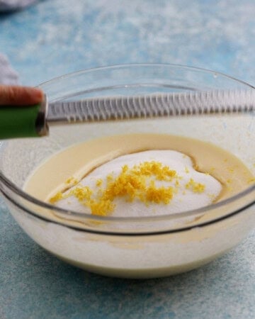 white sugar, yellow liquid and yellow lemon zest in a glass bowl.