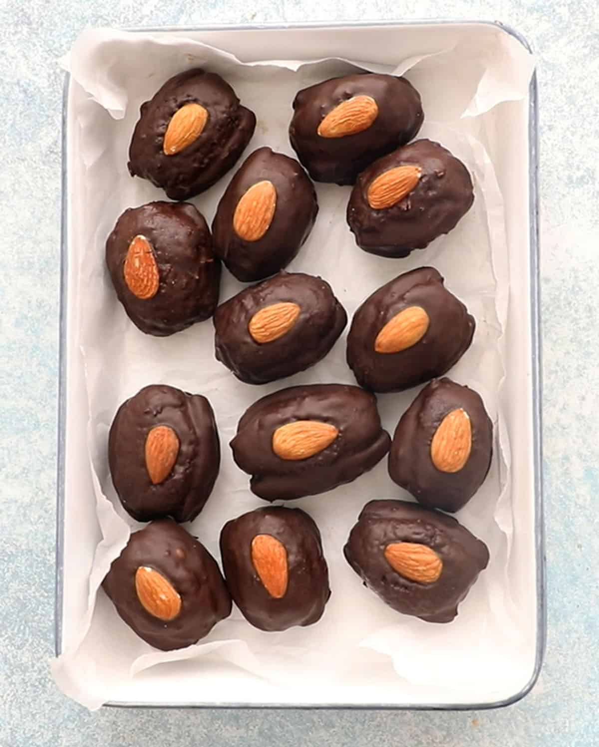 12 chocolate covered almond joy dates in a white tray.