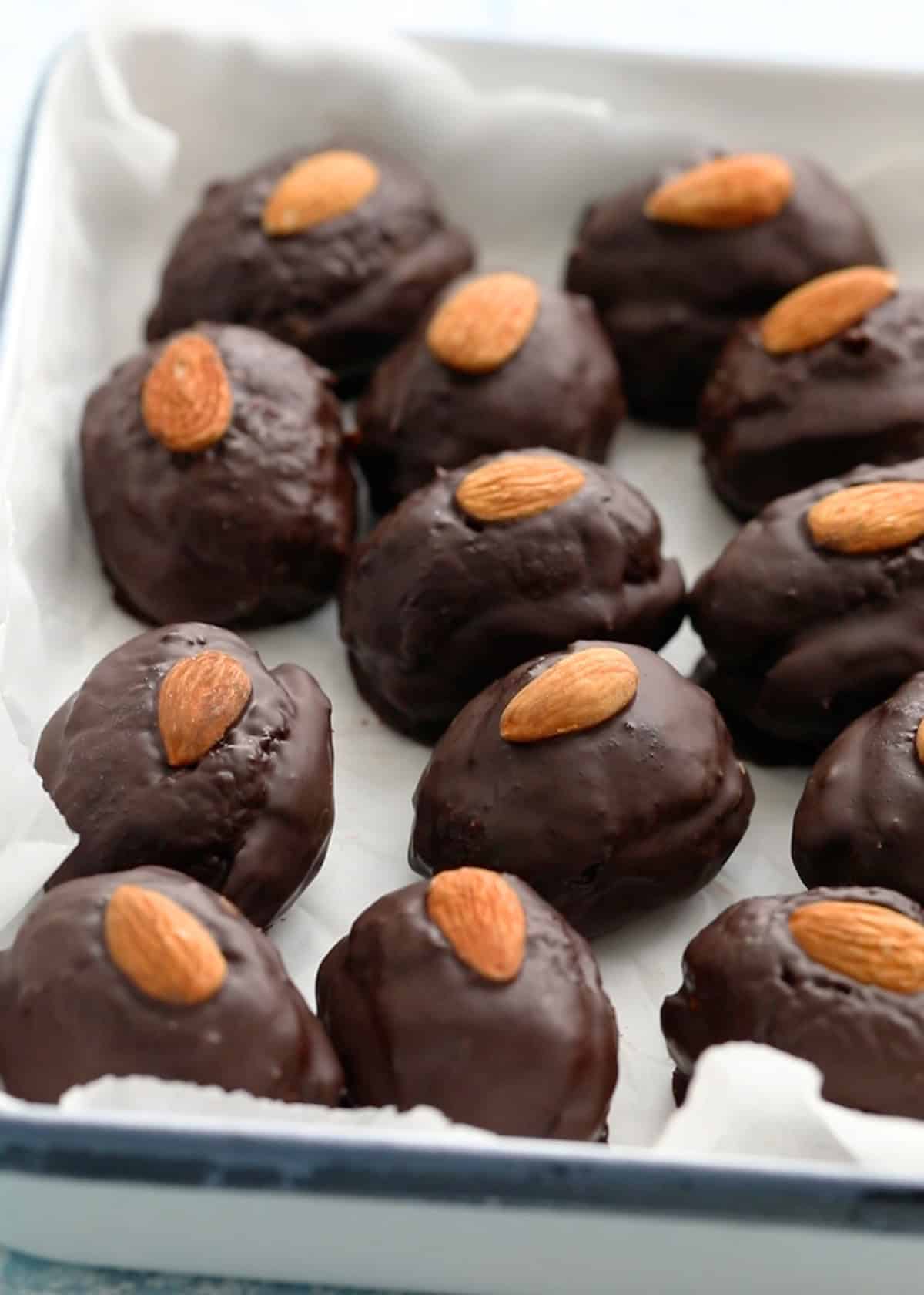 12 chocolate covered almond joy dates in a white tray.