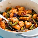 cooked chicken and green asparagus in a white pan.