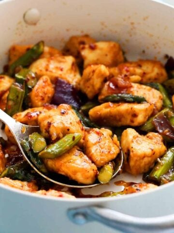 cooked chicken and green asparagus in a white pan.